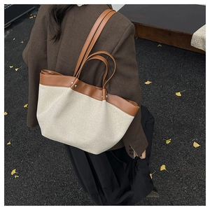 Detail of canvas tote bag with brown leather trim and handles in an outdoor setting