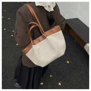 Detail of canvas tote bag featuring premium leather stitching and reinforced rivets