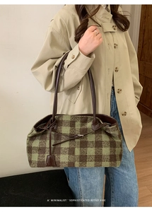 Retro green and brown checkered tweed tote bag with leather strap on beige coat