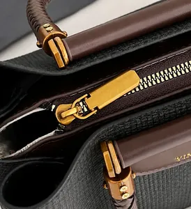 Detail eines goldenen Reißverschlusses und strukturiertem Stoff an einer Handtasche