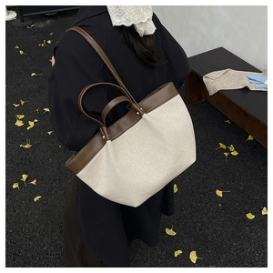 Detail of large beige canvas tote bag with brown leather straps in autumn street setting