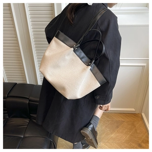 Detail of canvas tote bag with black leather patchwork and metal rivet reinforcement