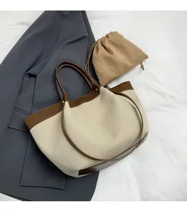 Canvas tote bag detail showing brown leather trim and beige fabric texture with inner pouch