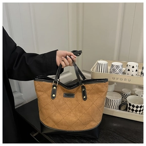 Detailed view of quilted stitching and faux leather paneling on the brown tote bag