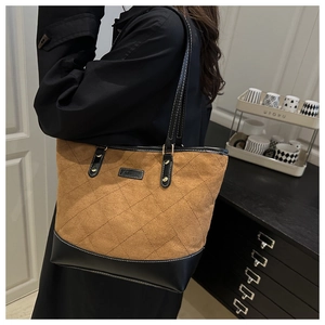 Detail of large tote bag with brown suede quilting and black leather contrast trim