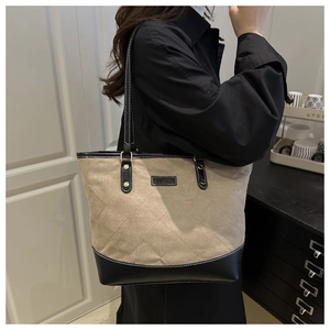 Detail of khaki quilted tote bag with black leather trim and Fashion label showing capacity