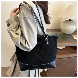 Detailed view of black tote bag with matte texture stitching and golden rivet details