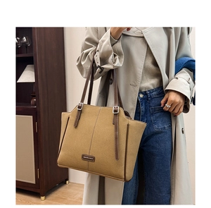 Schicke Khaki Canvas-Einkaufstasche mit braunen Ledergriffen, von einem Modell getragen