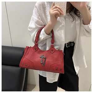 Detail of red vintage leather bag with silver cross, chains and rivet studs decoration