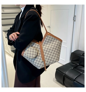 Detail of checkered tote bag with brown leather trim and matching round coin purse charm