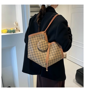 Detail of checkered tote bag with round coin purse charm shown on a model's shoulder