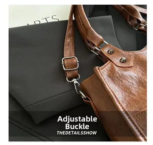 Detail view of vintage brown leather bag with silver studs and adjustable metal buckle