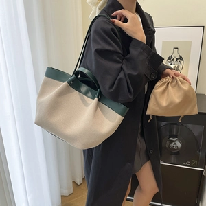 Chic beige canvas tote bag with dark green leather trim and matching drawstring pouch