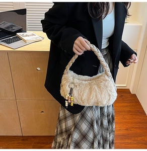 Détail du sac à main en peluche crème avec anse tressée et pompon en perles de bois