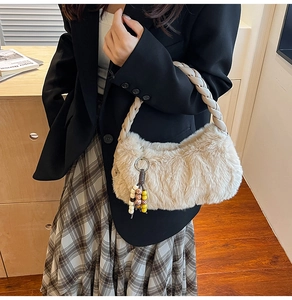 Détail d'un sac à main beige en fausse fourrure avec poignée tressée et pompon en perles bois
