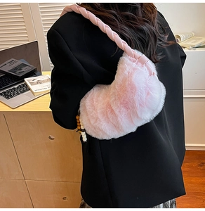 Détail du sac à bandoulière rose en fausse fourrure avec bandoulière tressée et pompon
