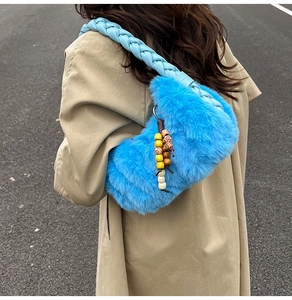 Détail du sac en fausse fourrure bleu vif avec bandoulière tressée et pendentif perlé