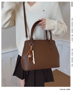 Detail of dark brown lychee texture leather handbag with colorful beaded tassel pendant