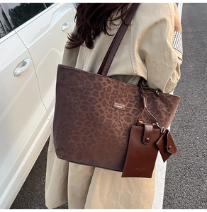 Detailansicht der Leopard-Einkaufstasche mit Metalllogo und kleinen Anhänger-Zubehör