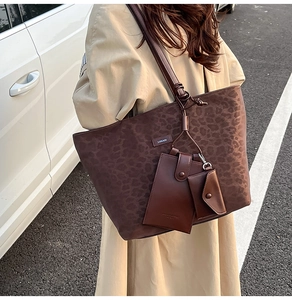 Details einer Leopard-Print Shopper-Tasche mit Anhängern auf einem beigen Trenchcoat