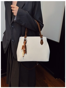 White lychee leather tote bag with brown straps and colorful wooden bead tassel