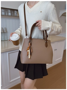 Detail of dark brown lychee leather handbag with ethnic beaded tassel and strap