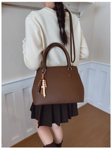 Detail of dark brown lychee leather handbag with colorful beaded tassel on a model
