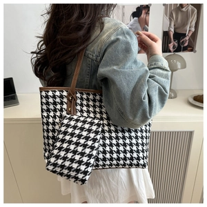 Detail of checkered houndstooth tote bag set with brown leather straps on model
