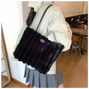 Detail of black plush striped tote bag with fashion tag on a female shoulder
