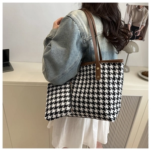 Detail of houndstooth tote bag with brown leather straps worn over the shoulder
