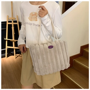 Detailed macro view of the soft beige plush tote bag featuring a vertical striped texture