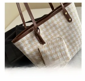 Close-up of woven tote bag with herringbone pattern and brown leather straps
