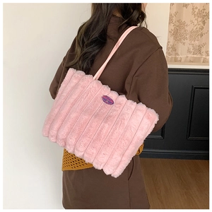 Pink plush tote bag with vertical stripes shown from behind on model shoulder