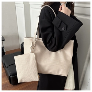 Detail of off-white tote bag with woven texture and small matching pouch on model