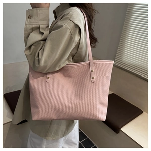 Close-up of pink tote bag showing subtle diagonal woven texture and metal rivets