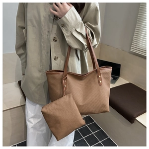 Brown woven tote bag with matching pouch shown in detail on a shoulder