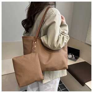Close-up of brown woven tote bag set with leather straps and gold metal rivet details