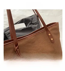 Detail of brown woven tote bag with leather handle, gold rivets and matching zipper pouch