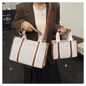 Detail of large canvas tote bag showing thick off-white fabric and brown leather handle