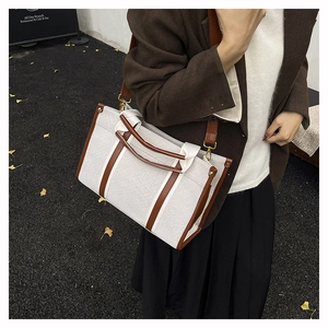 Detail of canvas tote bag with brown leather trim and adjustable crossbody strap