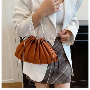 Detail of caramel pleated drawstring bag with white pearl handle and suede texture