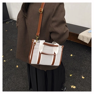 Close-up of a vintage canvas tote bag with brown leather straps on an autumn background