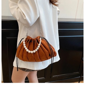Detail of caramel pleated bucket bag with pearl handle and silver chain strap