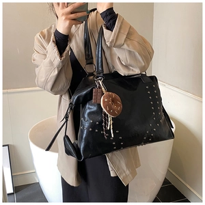 Close-up of black rivet tote bag with silver studs and cute dessert charms on camera
