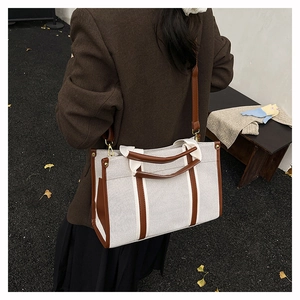 Detailed view of large canvas tote with brown leather trim and adjustable strap on a model