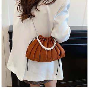 Detail of caramel pleated drawstring bucket bag with pearl handle and chain strap