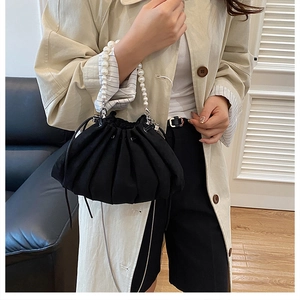 Detail of elegant black pleated drawstring bag featuring a luxury pearl bead handle accessory