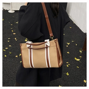 Detail of vintage canvas tote bag with brown leather handles and strap on autumn background