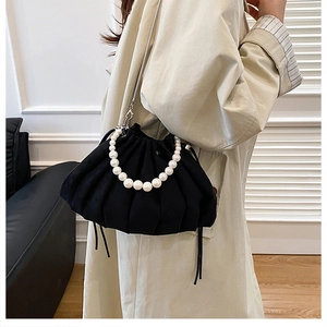 Detail of black pleated cloud bag with white pearl handle and silver chain strap