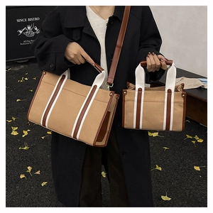 Detailed outdoor shot of khaki canvas tote set with brown leather trim and striped webbing